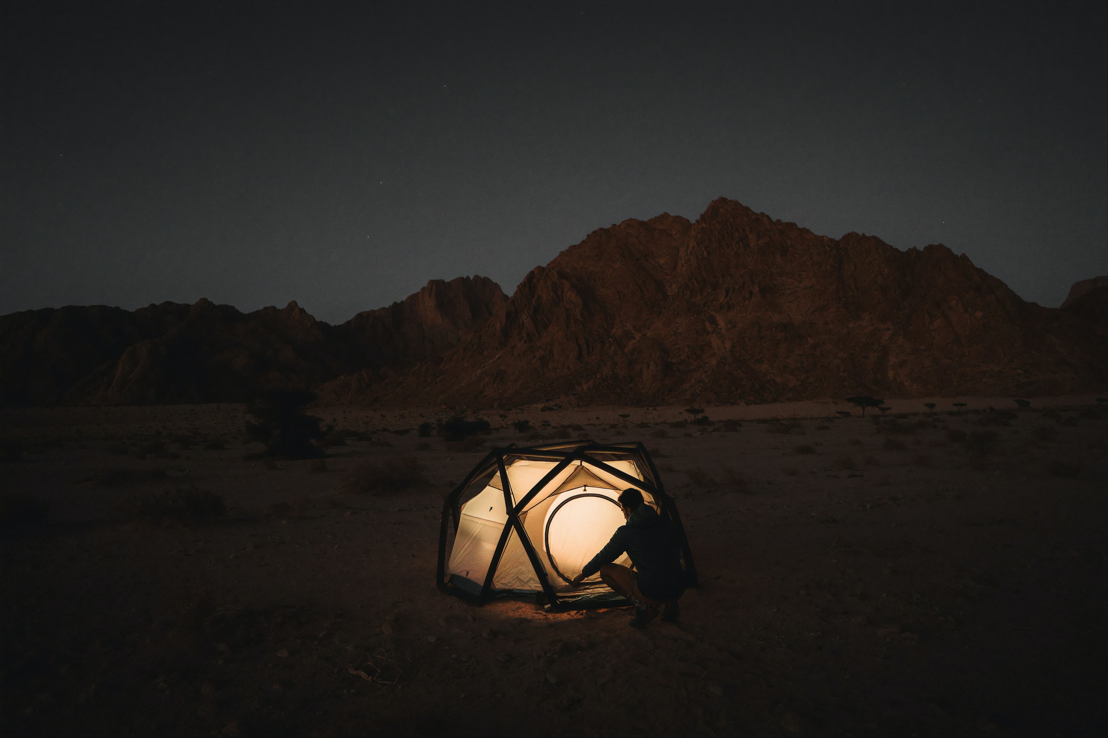 man writing on laptop infront of camping tent